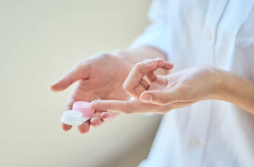 Person holding a scleral contact lens above a contact lens case.